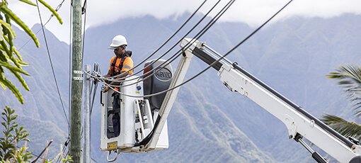 Technicien en équipement de sécurité travaillant sur un poteau électrique depuis une nacelle élévatrice